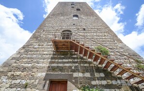 Un'alta torre in pietra con una scala in legno che conduce a una porta alla base.