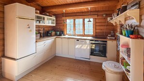 Eine Holzhüttenküche mit Kühlschrank, Geschirrspüler und Holzschränken.