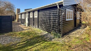 Eine Blockhütte mit Ziegelkamin, überdachter Veranda und Kiesauffahrt.