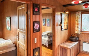A wooden cabin interior with a bed, a bench, and framed artwork on the walls. - 3 bedroom awesome home in Væggerløse (Væggerløse)
