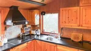 Una cocina con armarios de madera, una campana extractora negra, una ventana con vistas y un fregadero.