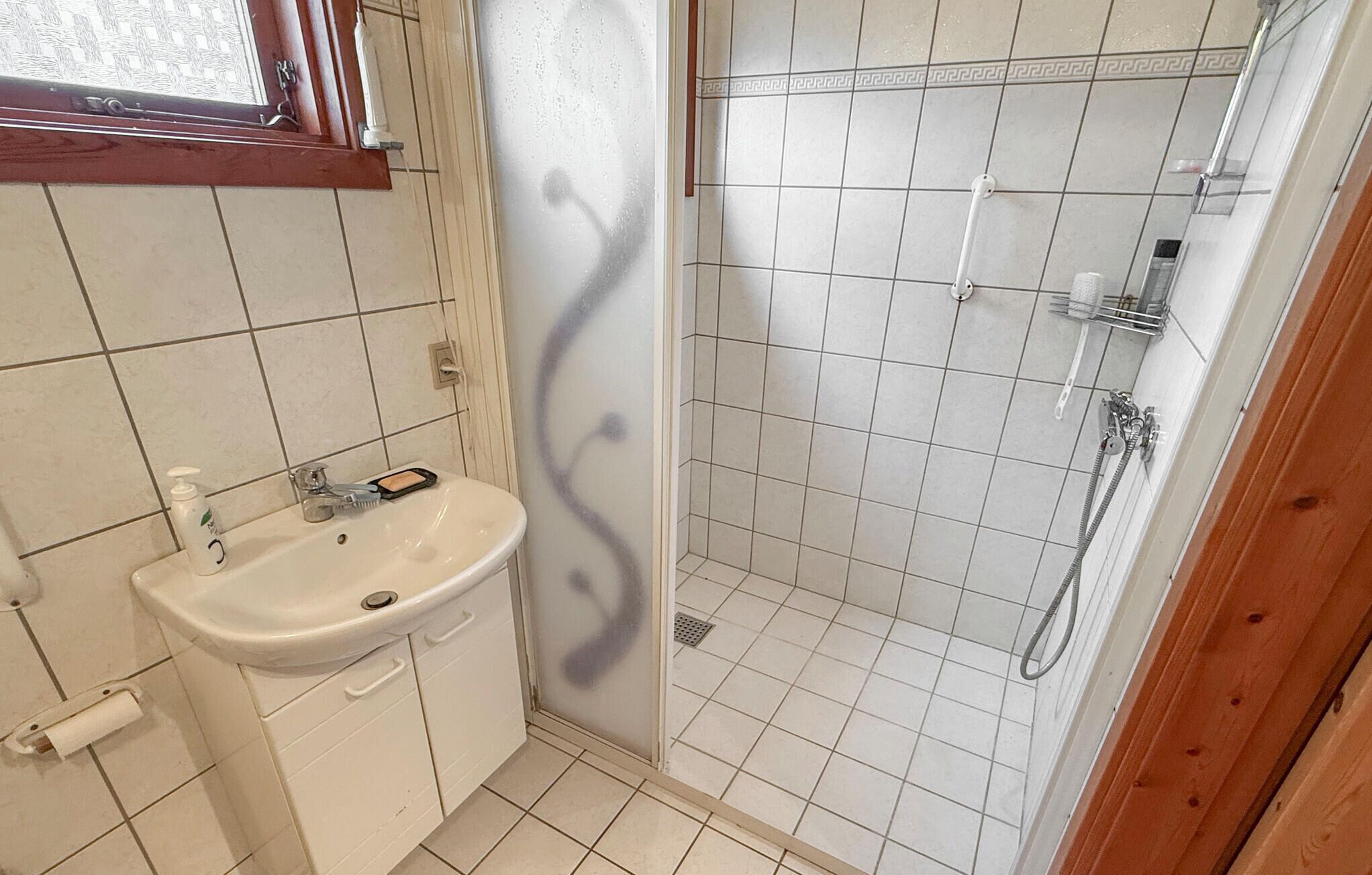A bathroom with a sink, a shower, and a window.