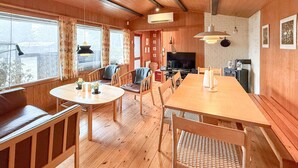 Un interior de madera con comedor, televisor y chimenea.