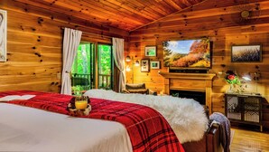 Un dormitorio de cabaña de madera con cama, chimenea y ventana grande.
