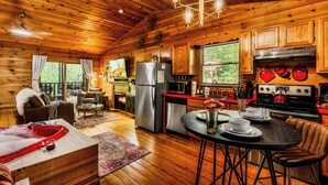 Interior de una cabaña de madera con cocina, comedor y un jacuzzi.