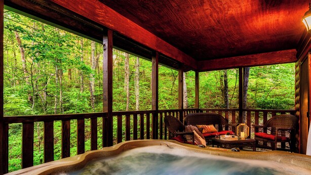 Un jacuzzi con muelle de madera y sillones de mimbre, rodeado por un bosque.