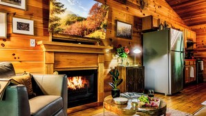 Interior acogedor de una cabaña con chimenea, paredes de madera, comedor y cocina.