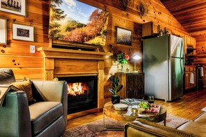 A cozy cabin interior with a fireplace, wooden walls, a dining area, and a kitchen. - "New Listing" Private, Romantic Couples Retreat-Sevierville TN (Sevierville)