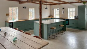 Een ruime keuken met een centraal eiland, houten balken en grote ramen.