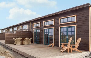 A wooden building with multiple windows and doors, a covered deck with outdoor furniture, and a clear sky. - Lovely home in Kivik with house a panoramic view (Kivik)