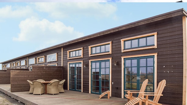 A wooden building with multiple windows and doors, outdoor seating, and a deck. - 1 bedroom cozy home in Kivik (Kivik)