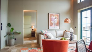 A modern living room with a sofa, a red chair, a coffee table with fruits, a lamp, and a painting on the wall. - 1 bedroom cozy home in Kivik (Kivik)