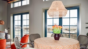 A dining area with wicker chairs, a round table with a patterned tablecloth, a vase with flowers, and a large wicker chandelier. - 1 bedroom cozy home in Kivik (Kivik)