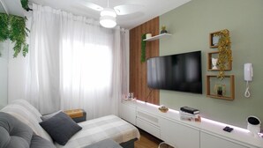 Una habitación moderna con una cama, un sofá, un televisor, un escritorio y un ventilador de techo.