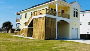 Ein zweistöckiges Haus mit Veranda, Garage und großem Vorgarten.