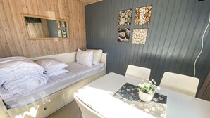 Een kamer met een bed, een tafel met een bloevas en een wand met ingelijste foto's.