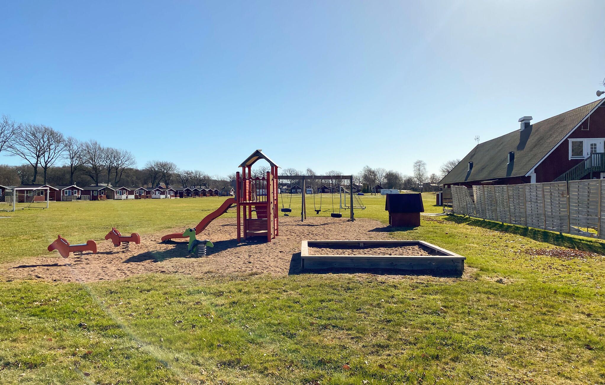 Ein Spielplatz mit Rutsche, Schaukeln und einer Kletterkonstruktion.