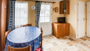 Un coin repas comprenant une table ronde, des chaises, une horloge, un buffet et une porte.