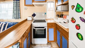 Une cuisine de taille réduite, équipée d’une cuisinière, d’un four à micro-ondes et d’un évier.