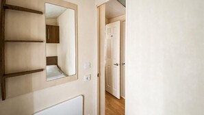 Un couloir avec un miroir, un radiateur et une porte donnant sur une autre pièce.