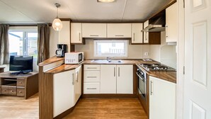 Une cuisine compacte équipée d’un four à micro-ondes, d’une cuisinière, d’un évier et d’un plan de travail en bois.