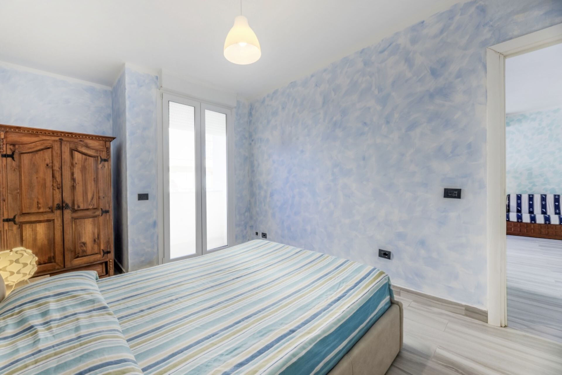 Ein Schlafzimmer mit einem Bett, einem Holzschrank und einem Fenster.