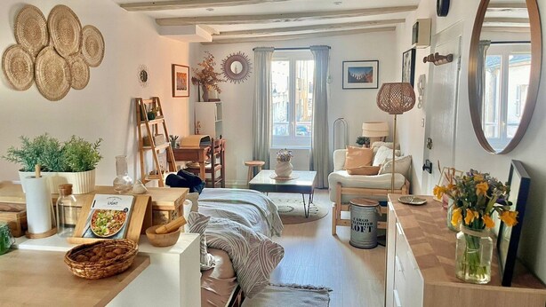 Un accogliente soggiorno con divano, tavolo da pranzo, libreria e un grande specchio.