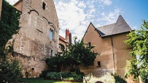 Un edificio storico con una torre, un cortile e un albero.