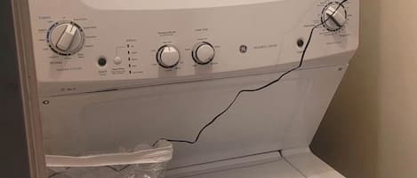 A front view of a washing machine with control knobs, a lint filter, and a Ben Dempsey detergent package.