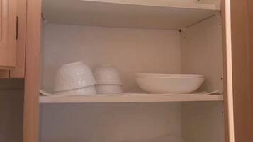 A wooden cabinet with shelves containing white bowls and plates.