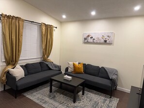 A living room with a dark-colored sofa, a coffee table, and a patterned rug. - Lovely Beacon Heights (Edmonton)