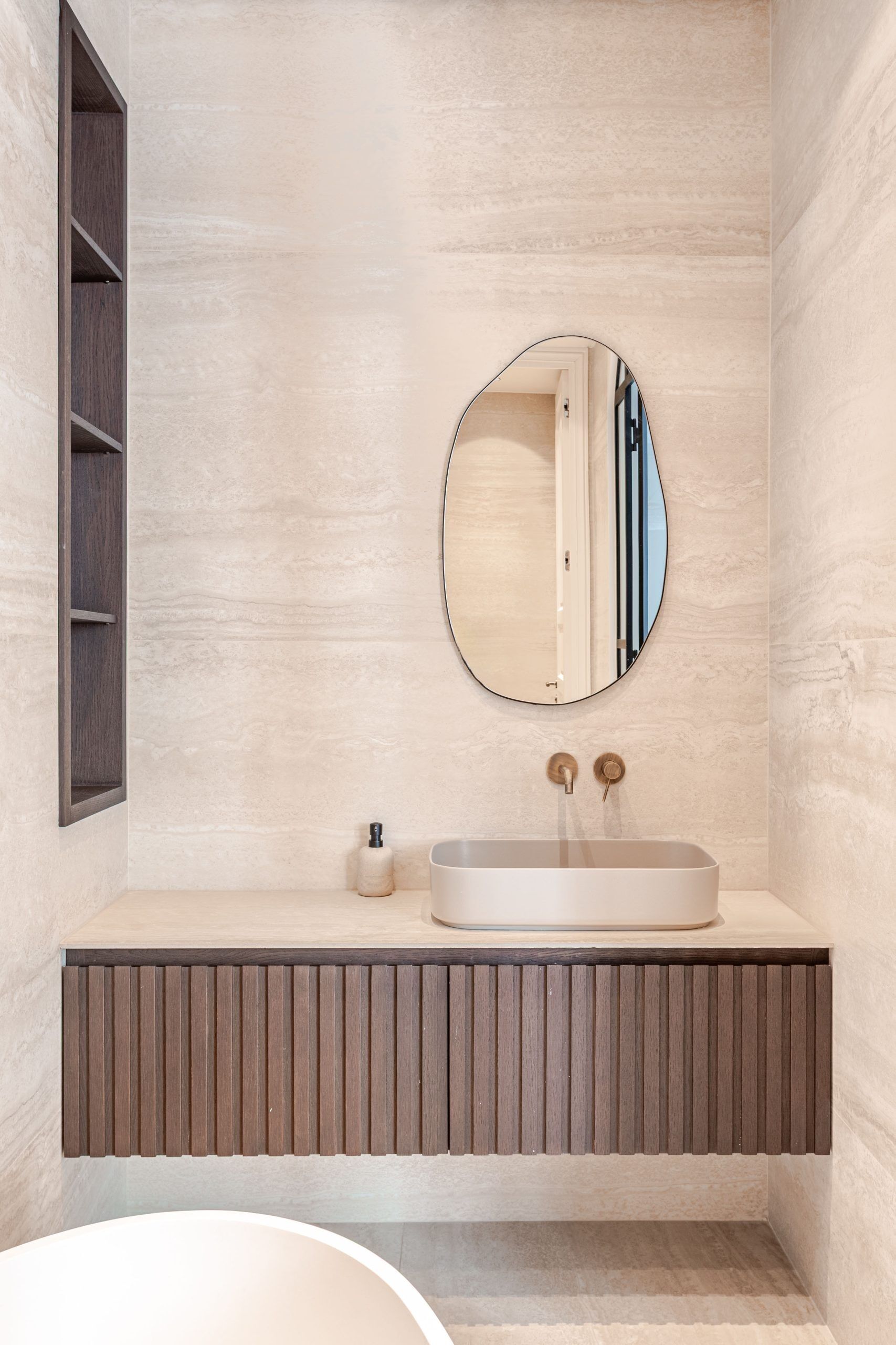 Une salle de bain avec un meuble-lavabo en bois, un miroir rond et une baignoire.