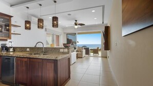 Una cocina moderna con una isla central, iluminación colgante y vistas al exterior.