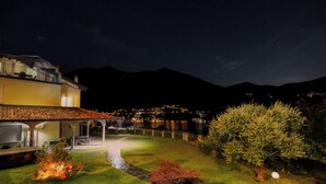 Una casa con un patio, un prato e una montagna sullo sfondo.