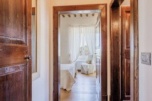 A wooden door leading to a bedroom with a bed, a chair, and a window with curtains. - Italian Experience- Serafini Holiday Home (Bargni)