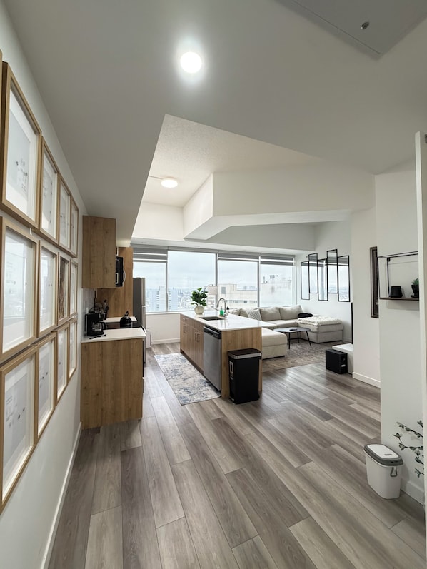 A modern kitchen with wooden cabinets, a central island, and a dining area with a sofa and coffee table.
