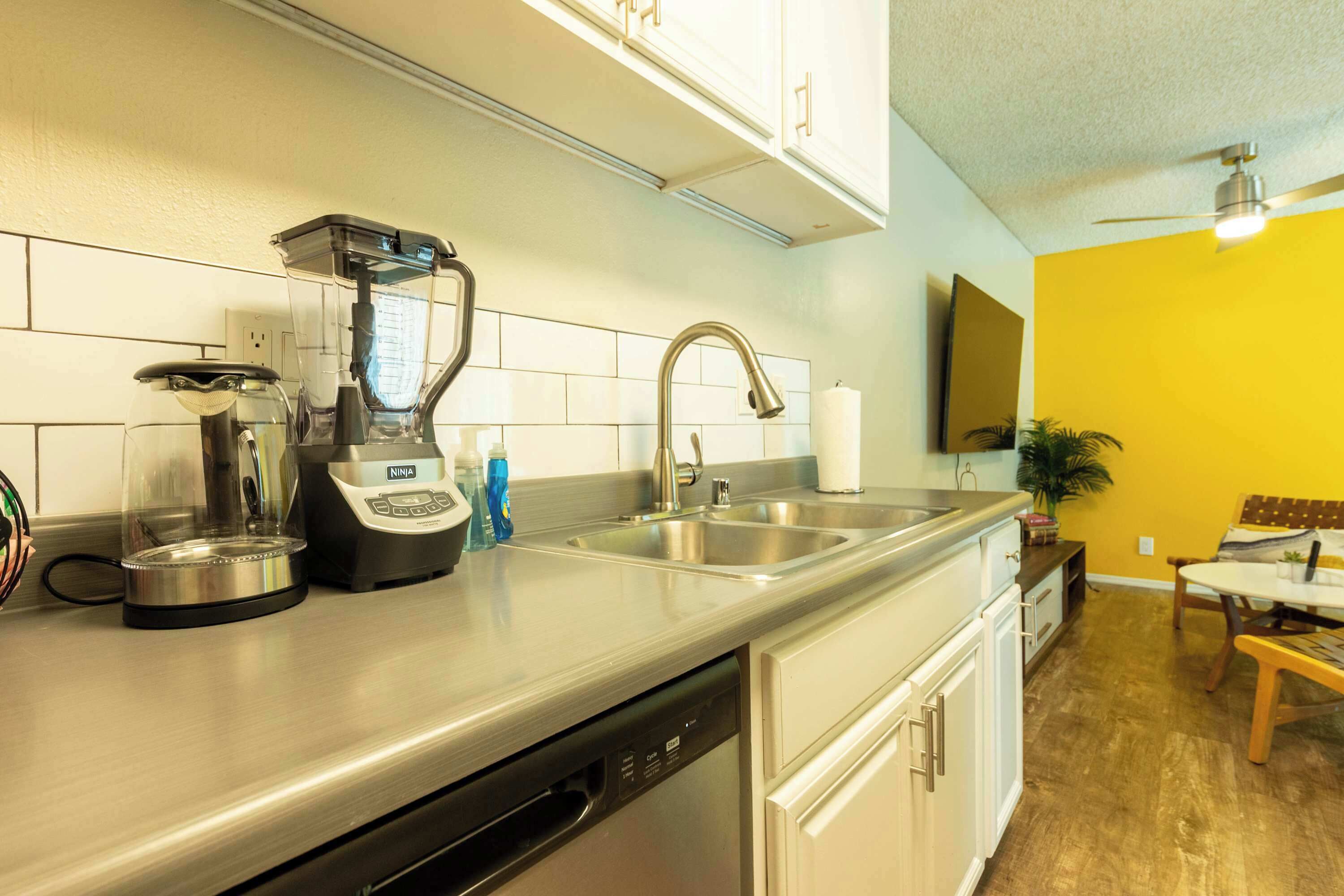 A modern kitchen with a built-in dishwasher, a coffee maker, and a sink.