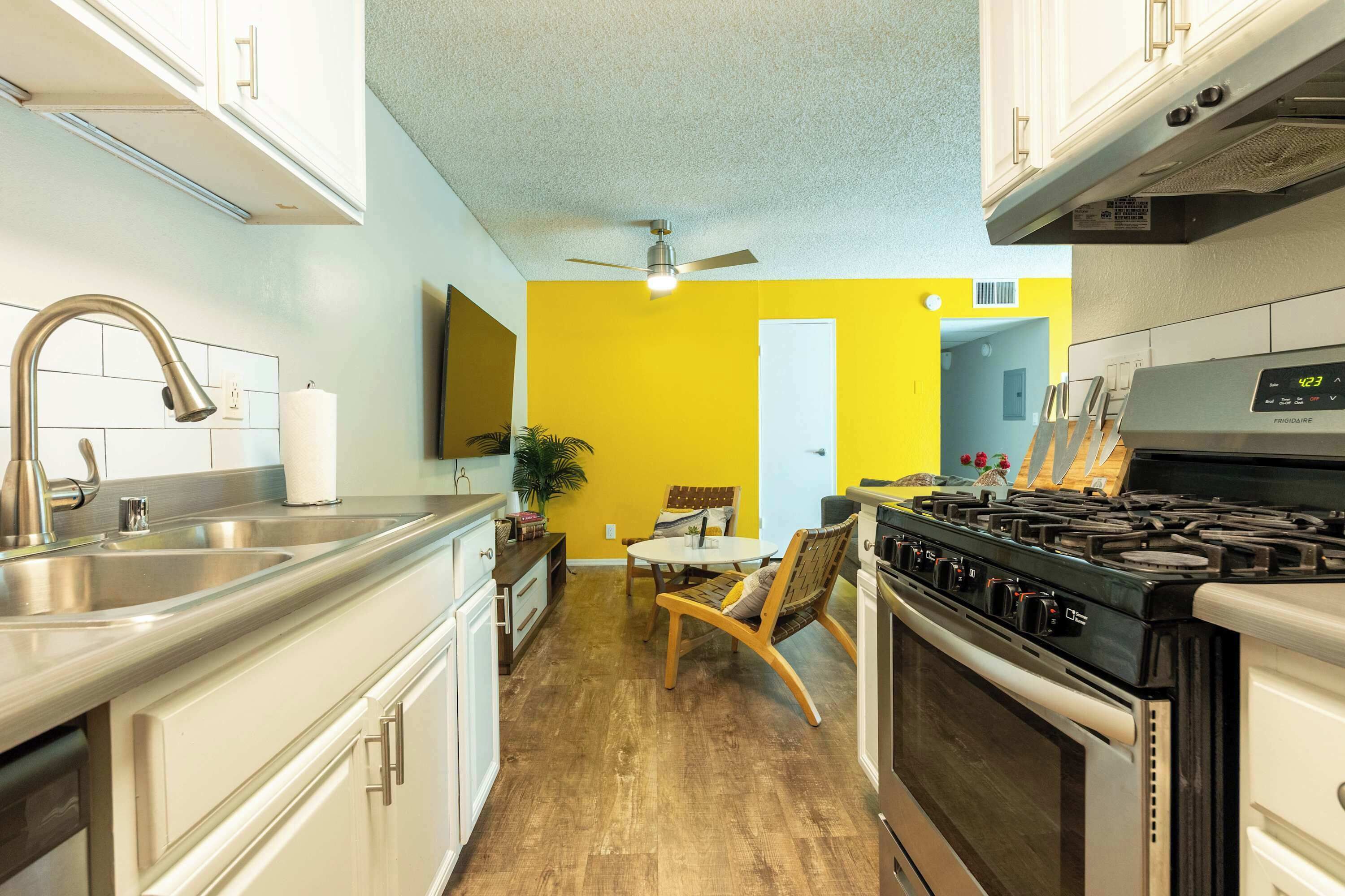 Una cocina con estufa, fregadero y ventilador de techo.