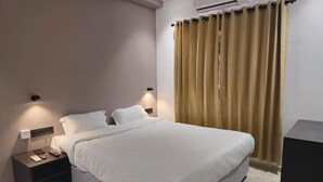 A modern bedroom with a large bed, bedside tables, and an air conditioning unit. - 7 The Business Hotel (Aluva)