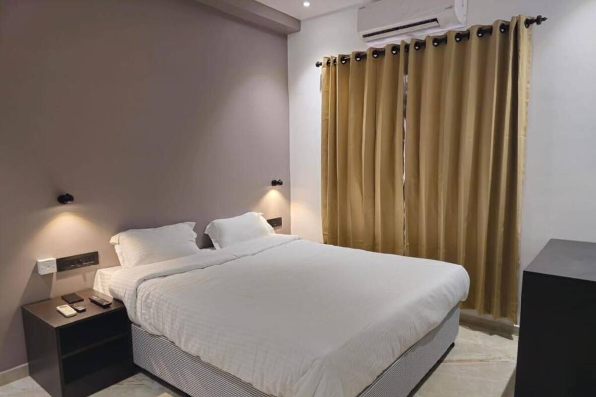 A modern bedroom with a large bed, bedside tables, and an air conditioning unit.