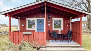 A small red cabin with a porch, two windows, and a door.