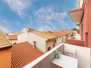 A rooftop terrace with terracotta tiles, a potted plant, and a white balcony railing. - Appartamento con Aria Condizionata (Trinità d'Agultu e Vignola)