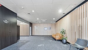 Una sala de conferencias con un panel de señalización de incendios, un sofá, una planta en maceta y una silla.