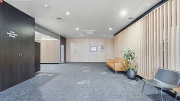 A conference room with a fire indicator panel, a sofa, a potted plant, and a chair.