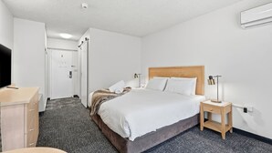 Una habitación de hotel con cama, mesita de noche, lámpara y escritorio con silla.