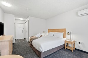 A hotel room with a bed, bedside table, lamp, and a desk with a chair. - King Room w/ Balcony Views (Hobart)