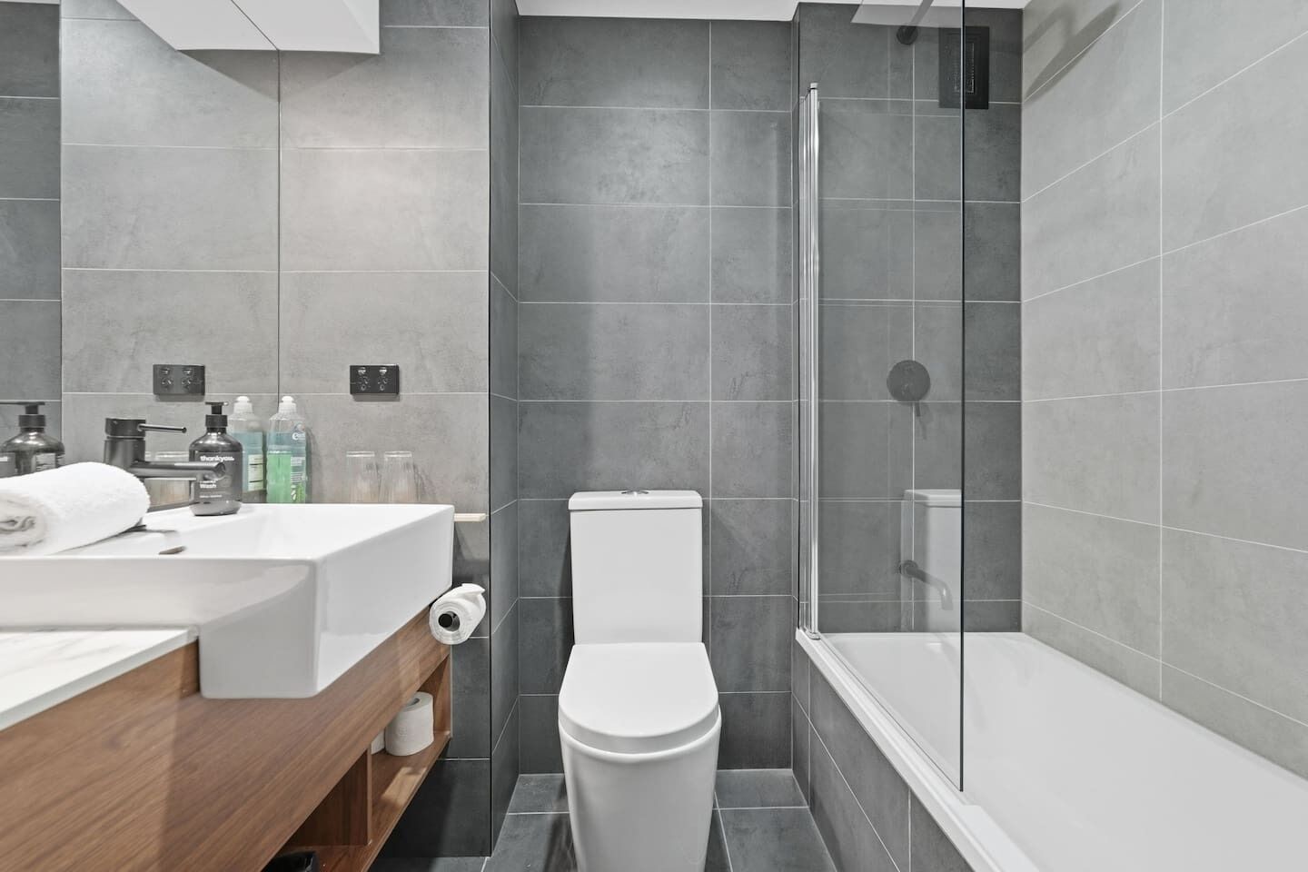 A modern bathroom with a shower, toilet, and sink.