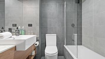 A modern bathroom with a shower, toilet, and sink.