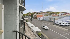 Vista de la calle con un edificio que tiene un balcón, una carretera con coches y un cartel de 'birchalls'.