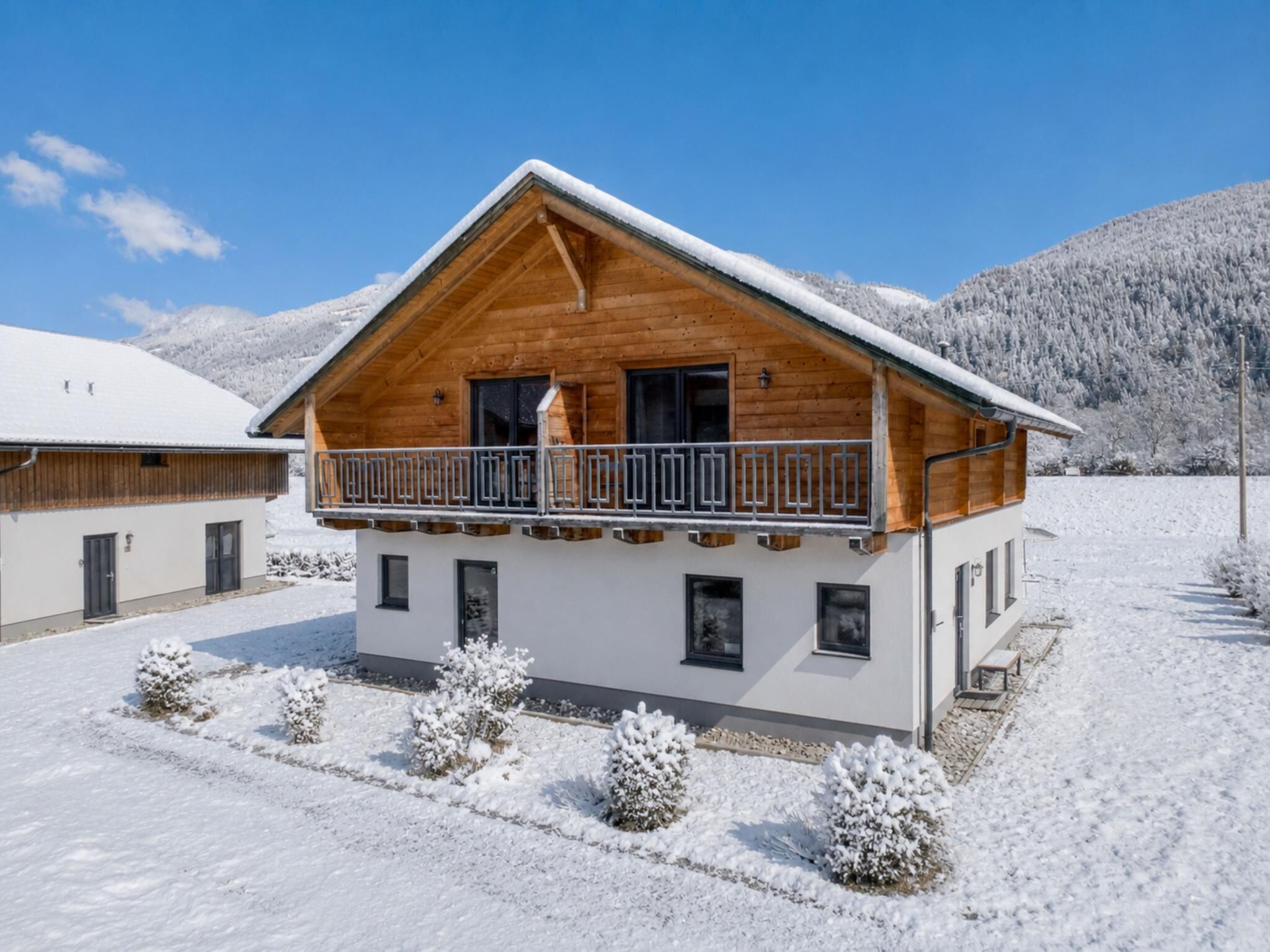 Una cabaña de madera con balcón, rodeada de nieve y montañas.